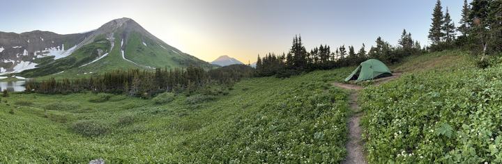 Dusk panorama of the Windfall Lake campsite below a green peak