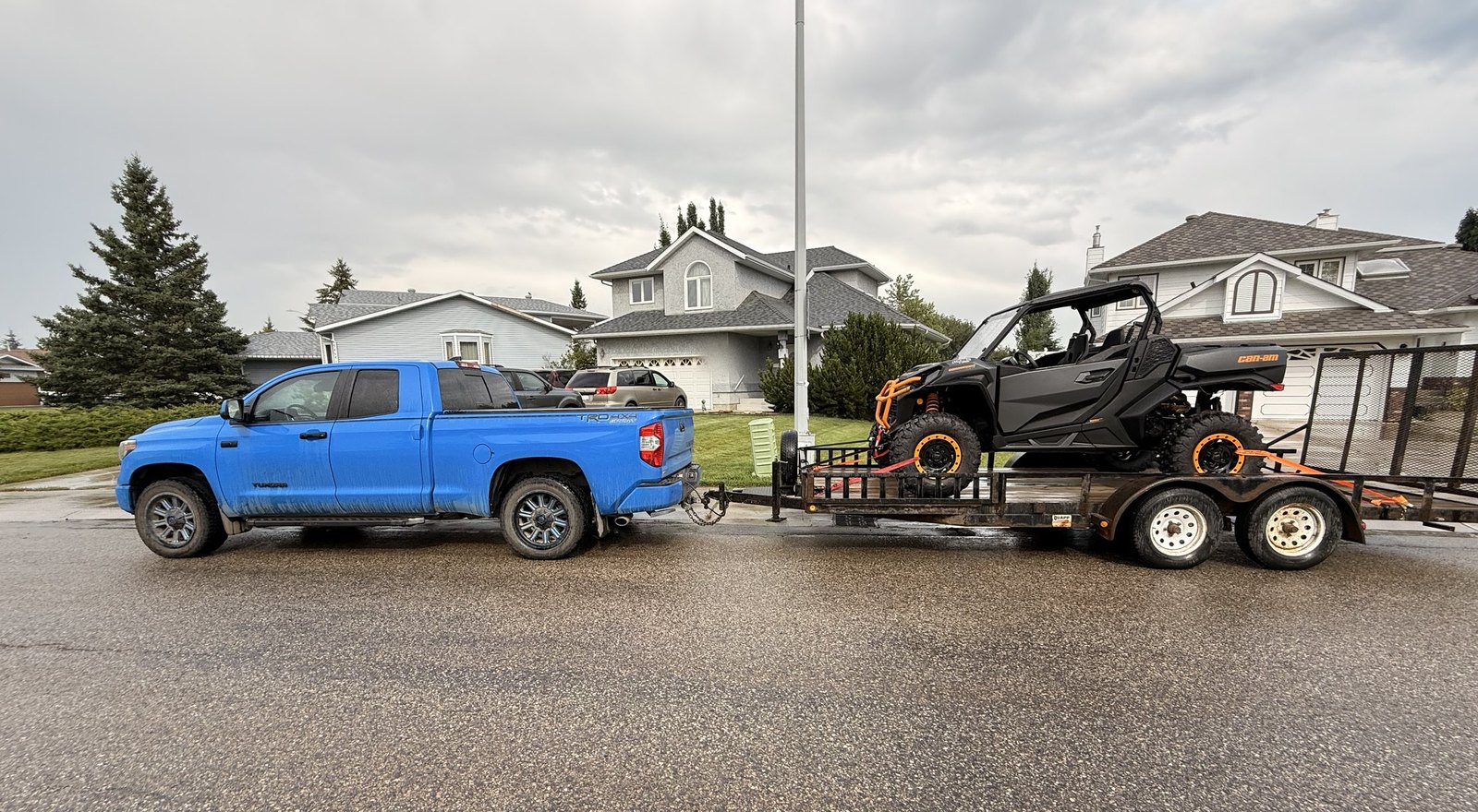 The Voodoo Blue Toyota Tundra hitched to the trailer with the Can-Am Commander strapped down on the deck